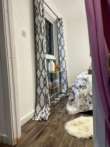 a bedroom with a window with curtains and a wooden floor at Farm woodland riverview cabin bbq firepit pet friendly in Hertford