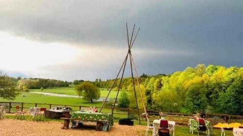 a field with a windmill in the middle of a field at Farm woodland riverview cabin bbq firepit pet friendly in Hertford
