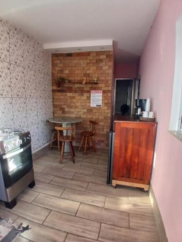a room with a table and a kitchen with a stove at kitnet pé na areia reservado por sayonara in Ilhéus