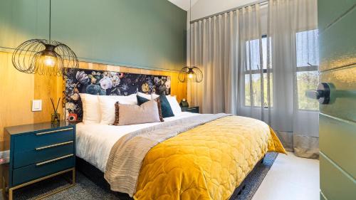 a bedroom with a large bed with a yellow blanket at The Royal Junction in Riebeek-Kasteel