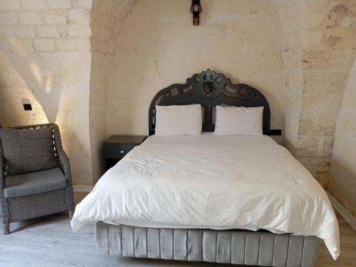 a bedroom with a white bed and a chair at Aslan Guest House in Sanlıurfa