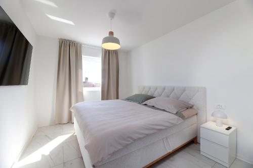 a white bedroom with a bed and a window at SPA Apartment Mediterano in Rijeka