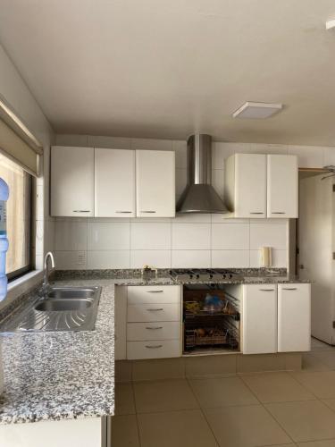 a kitchen with white cabinets and a sink at Casa Amplia y Comoda SyS Suites in Chicureo Abajo