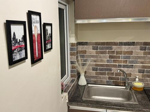 a sink in a kitchen with pictures on the wall at The Chess Lounge with Pool & Gym in Islamabad