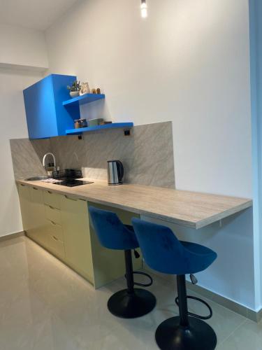a kitchen with two blue bar stools at a counter at Viridian Three Accommodation, Studio 2 in Valjevo