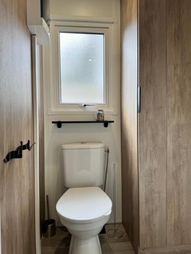 a bathroom with a white toilet with a window at Location Mobil-Home "Le Piriac'Home V2" in Piriac-sur-Mer