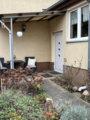 a house with a porch with a door and a chair at FeWo am Mainplatz in Teltow