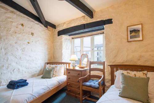 a bedroom with two beds and a dresser and a window at The Wheel House in Penzance
