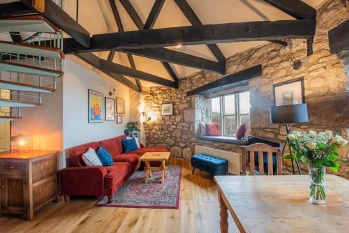 a living room with a red couch and a stone wall at The Wheel House in Penzance