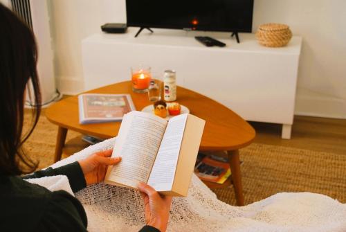 une femme qui lit un livre devant une table dans l'établissement Confortable T2 sur les rives de la Charente, à Angoulême
