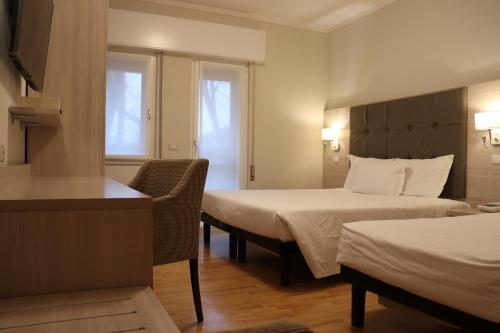 a hotel room with two beds and a chair at Hotel Montereale in Pordenone