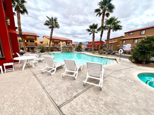 a pool with chairs and a table and palm trees at Supreme updated Hawkridge Condo in Mesquite