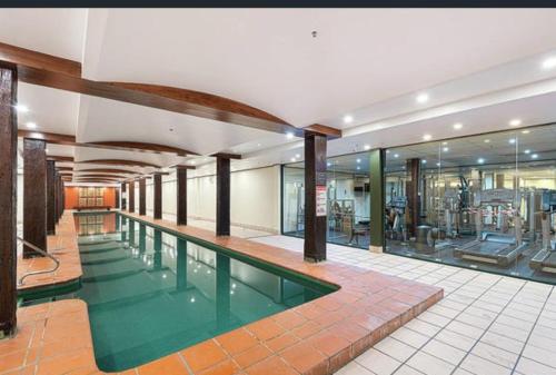 a gym with a swimming pool in a building at Darling Harbour Apartment - Weekend Getaway in Sydney