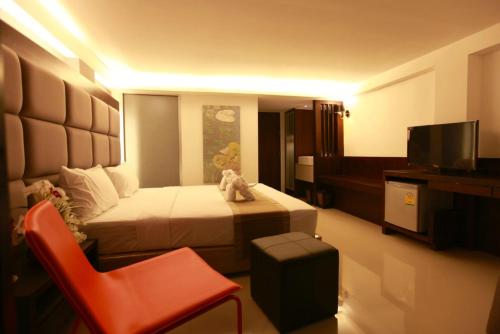ein Hotelzimmer mit einem Bett und einem roten Stuhl in der Unterkunft The Bangkok Major Suite in Bangkok