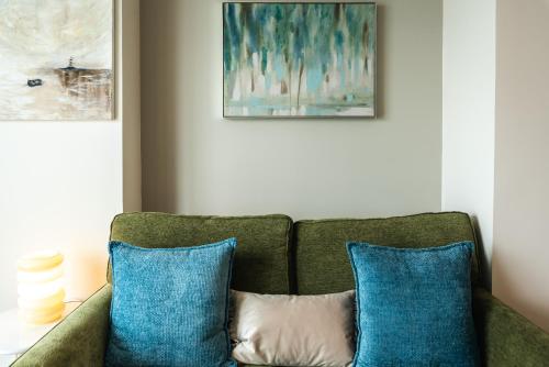 a green couch with two blue pillows in a room at The Itchen River Apartments in Southampton