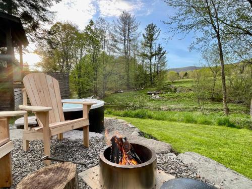 a fire pit with a wooden chair and a bench at Le 10 - Spa Sauna Shower Bromont Lac-Brome in Bromont