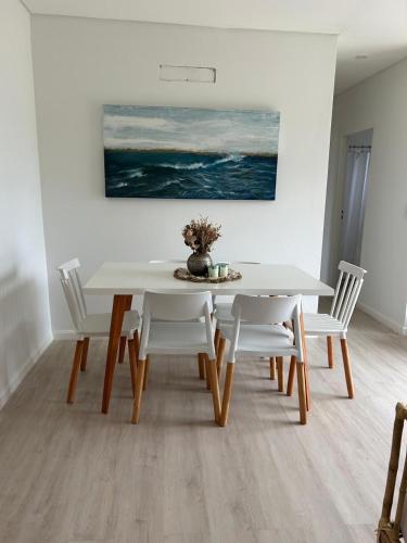 a white dining room table with white chairs and a painting at Casa Contenedor Chapadmalal in Chapadmalal