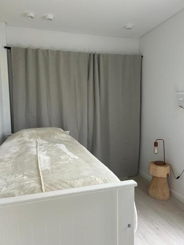 a white bed in a bedroom with a curtain at Casa Contenedor Chapadmalal in Chapadmalal