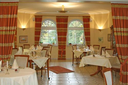 un restaurante con mesas y sillas blancas y ventanas en Hostellerie Bacher, en Neunkirchen