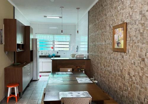 eine Küche mit einem Tisch und einer Ziegelwand in der Unterkunft Cantinho aconchegante da Família Moreira na Praia das Palmeiras in Caraguatatuba
