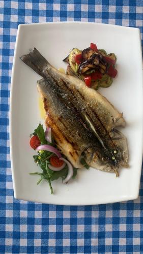 two fish on a plate with salad on a table at Vila Rahmi & Veli Dervishaj in Vlorë