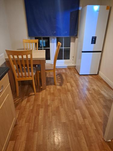 a kitchen with a table and chairs and a refrigerator at Mekees Luxury Apartment Toronto Wing in Tipton