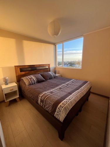 a bedroom with a bed and a large window at Departamento acogedor y céntrico in Temuco
