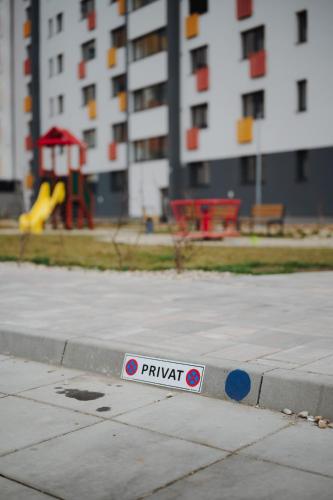 a sign on a sidewalk with a playground in the background at Bluetto in Trnava