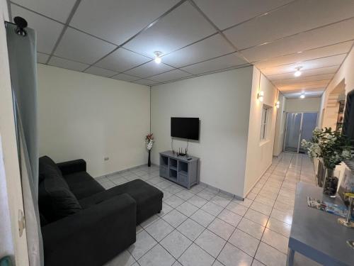 a living room with a couch and a flat screen tv at Casita Leao - Juayua, Sonsonate in Juayúa