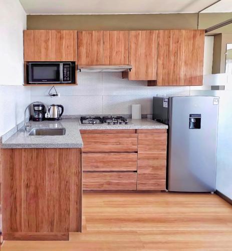 Una cocina con gabinetes de madera y un refrigerador de acero inoxidable. en Misti Loft, en Arequipa
