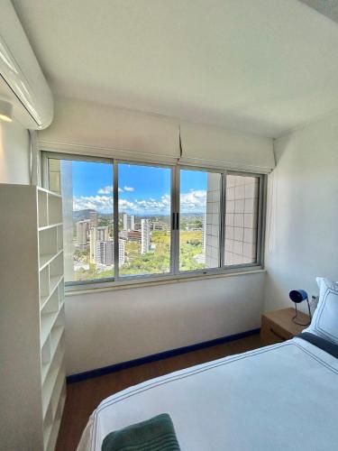 a bedroom with a bed and a large window at Linda cobertura duplex com varanda no Vila da Serra in Nova Lima