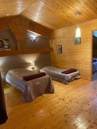 deux lits dans une chambre avec des murs et du parquet en bois dans l'établissement LE GîTE DES DAINES, à Lavans-lès-Saint-Claude