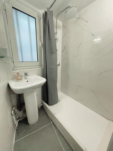 une salle de bain blanche avec un lavabo et une douche dans l'établissement Mon Amour Vavin, à Paris