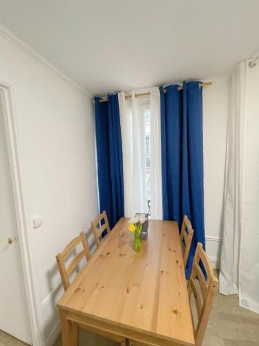une salle à manger avec une table en bois et des rideaux bleus dans l'établissement Mon Amour Vavin, à Paris