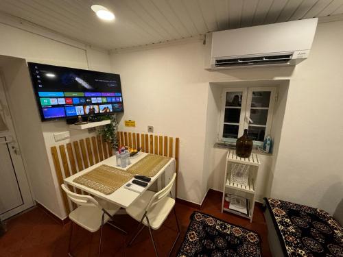 a room with a table and a tv on the wall at Sobreira Stone Cottage in Peso da Régua