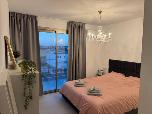 a bedroom with a bed with a chandelier and a window at Brandnew Rooftop Flat near Larnaca Mall in Larnaca