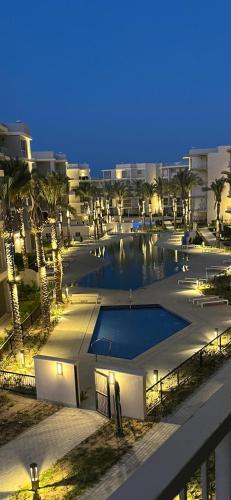 a large swimming pool in a city at night at Chalet in marassi marina pool view exm80 in El Alamein