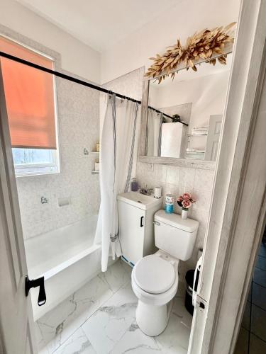 a white bathroom with a toilet and a bath tub at Apart Studio 12mint From New York City Times Square in West New York