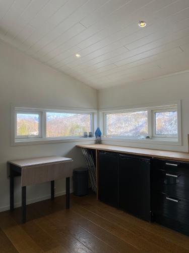 a kitchen with a table and two windows at Practical and cozy cottage in idyllic Senja 3 bedrooms in Senja