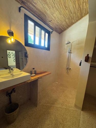 une salle de bain avec un lavabo, un miroir et une douche dans l'établissement Nino Lodge, à Samba Dia