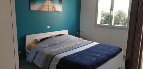 une chambre avec un lit avec un mur bleu dans l'établissement Maison de vacances, à Pézenas