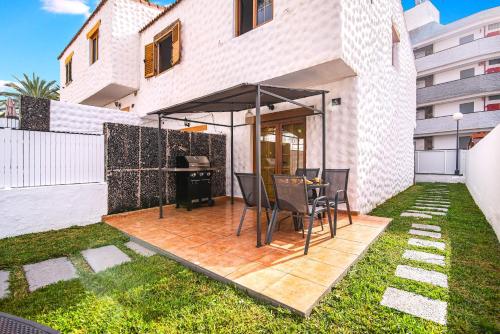 a patio with a table and chairs in a backyard at Paradise Dúplex Garden & Beach Maspalomas in San Bartolomé