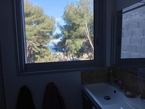 a bathroom with a window and a sink and trees at Villa vu mer et étang de thau in Sète