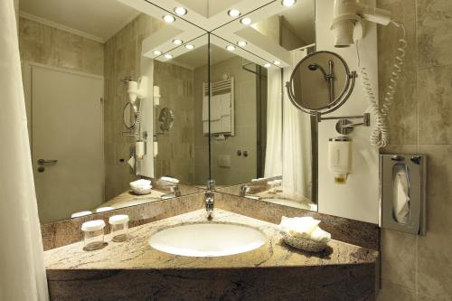 a bathroom with a sink and a large mirror at SOALTEE Hotel by Trip Inn Frankfurt Messe Tagungshotel in Frankfurt/Main