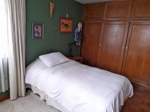 a bedroom with a white bed and wooden cabinets at Casa en Obrajes in La Paz