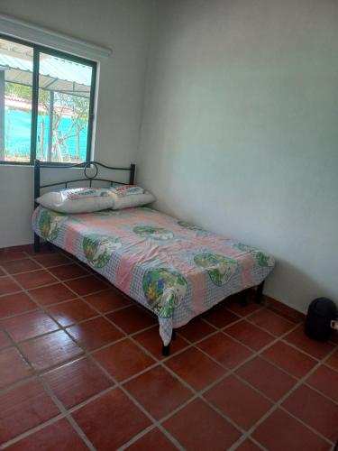 a small bed in a room with a tiled floor at Finca Buganvilia in Anolaima