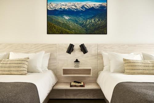 two beds in a room with mountains in the background at AutoCamp Sequoia in Three Rivers