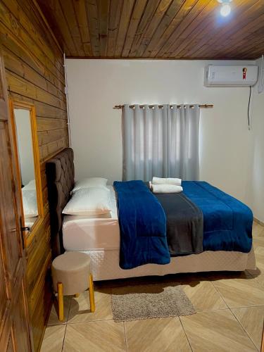 a bedroom with a bed with a blue blanket at Casa Jardinada in Pomerode