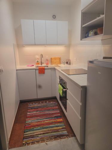 - une cuisine avec des placards blancs et un tapis au sol dans l'établissement Lidou, à Menton