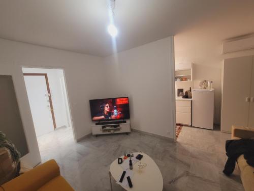 un salon blanc avec une télévision et une table dans l'établissement Lidou, à Menton